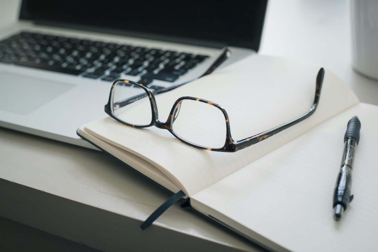 Reading glasses on a notebook beside a laptop — online therapy for South Carolina residents