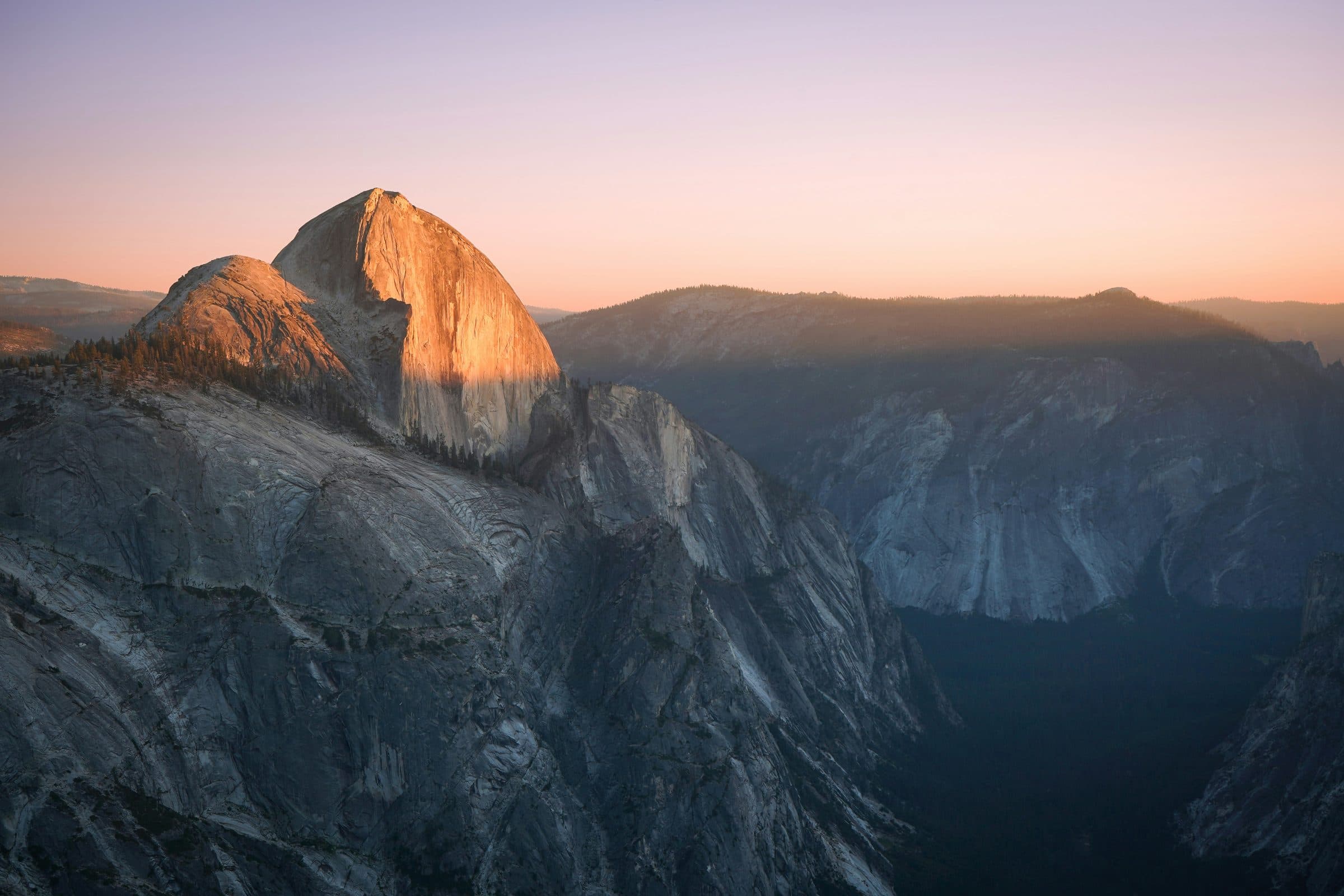 A granite mountain dome catching the first light of dawn above a dark ridgeline